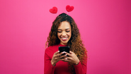 Cute young woman dressed for Valentines Day on dating app cellphone, studio - Powered by Adobe