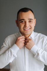 A man poses and fastens a black jacket. Portrait of the groom. Fashion and style. Business