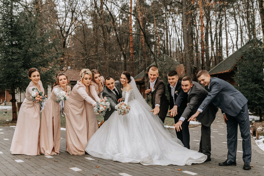 Bride and groom hugging, posing with friends. Friends are having fun. Happy moments. Wedding portrait in nature, wedding photo in light colors.