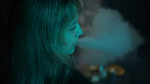 Girl smokes vape in neon light