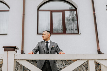 Portrait. The groom poses against the background of the hotel. Business style. Winter wedding