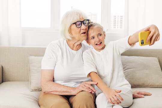 Education family grandmother call hugging togetherness child granddaughter sofa phone video bonding smiling selfie