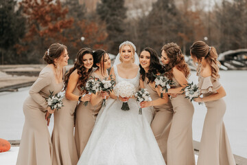 The bride and her bridesmaids pose holding bouquets and looking at the bride. Winter wedding