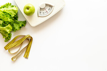 White floor weight scales with greenery and healthy food. Diet and body weight control concept