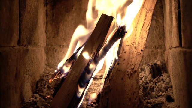 Medium shot of wooden logs burning in an indoor fireplace.