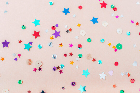 Colorful confetti on beige background. Christmas, New Year, Birthday party concept. Top view, flat lay