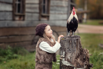 Girl with hen near farm house in  countryside at autumn
