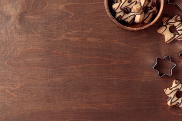 Wooden background with fresh baked homemade star-shaped cookie, wooden bowl and cutters