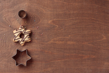 Obraz na płótnie Canvas Wooden background with fresh baked homemade star-shaped cookie with chocolate and cookie cutters
