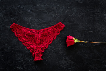 Elegant red lace lingerie bikini panties with red rose, top view - obrazy, fototapety, plakaty