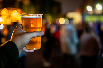 plastic cup glass with beer in hand. Outdoor summer festival