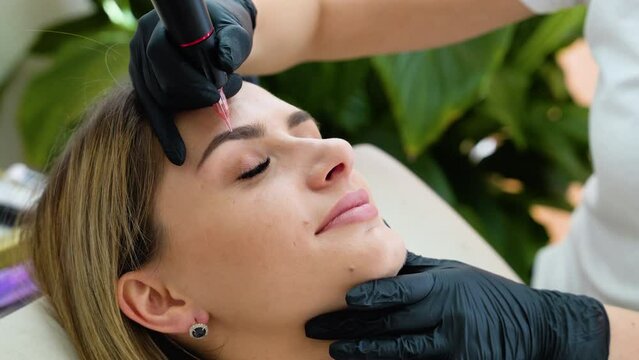 Permanent makeup artist makes eyebrow makeup in a beauty salon