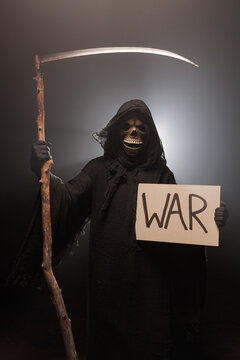 The Grim Reaper holds a poster with the inscription war. The scary grim reaper. Death Grim Reaper Costume for Halloween. Halloween characters concept.