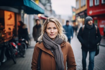 Portrait of a beautiful young blonde woman in a coat and scarf on a city street