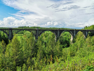 Fototapeta na wymiar Railway bridge across the river in the south of the Kama region. The old Big Sars viaduct. The abandoned Oktyabrsky viaduct in the Perm Region. Russia.