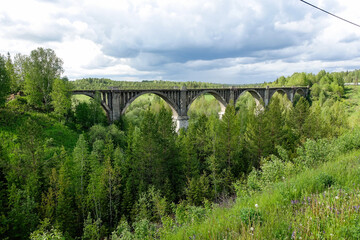 Fototapeta na wymiar Railway bridge across the river in the south of the Kama region. The old Big Sars viaduct. The abandoned Oktyabrsky viaduct in the Perm Region. Russia.
