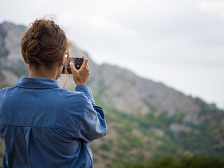 Fototapeta premium girl takes pictures of mountain landscape on her phone