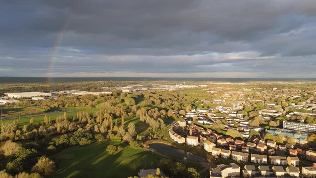 Reverse aerial view of Gloucester park and the new houses by the lake under a rainbow