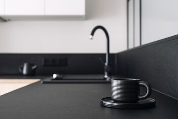 Coffee cup on black kitchen countertop against blurred modern interior