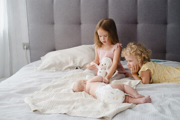 Obraz na płótnie Canvas Siblings look at newborn baby