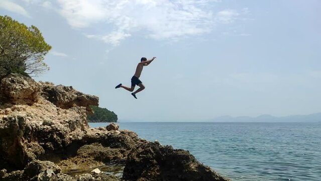 Slow motion clip of  man jumping from cliff to water in Croatia.