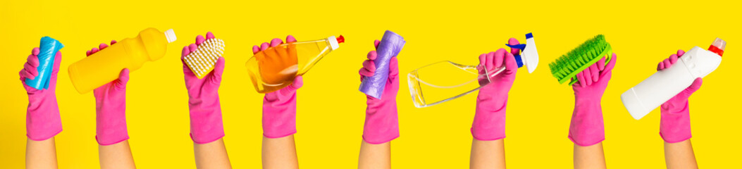 Hand with  rubber glove holding cleaning products on a yellow background. banner. Cleaning concept.