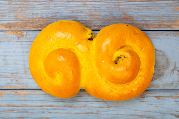 one s shaped traditional saffron bun on blue wooden background