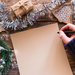 Writing a wish list Christmas letter on a wooden background with decorations