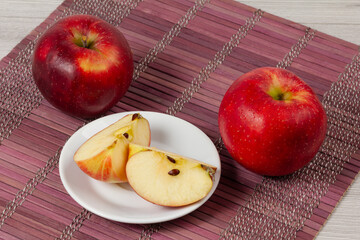 Red apples with a saucer on the bamboo napkin.