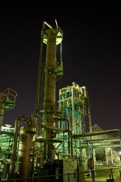 Industrial plant illuminated in a vibrant green hue during the evening hours