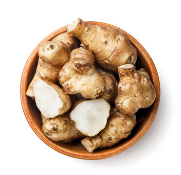 Jerusalem artichoke and half in a wooden plate on a white background. Top view