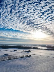 Aerial view of a winter landscape with fluffy clouds over it and distant hills in Indiana