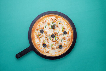 olives and capsicum pizza with wooden pan on green background