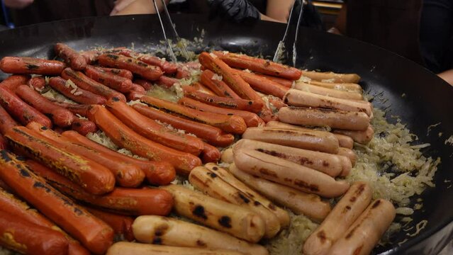 Street food hot dog - grilled German or Bavarian Nuremberg sausages with cabbage sauerkraut on a huge pan bowl at market.