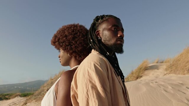 A young couple with Afro and dreadlocks standing back to back, symbolizing the unity and connection within the black community
