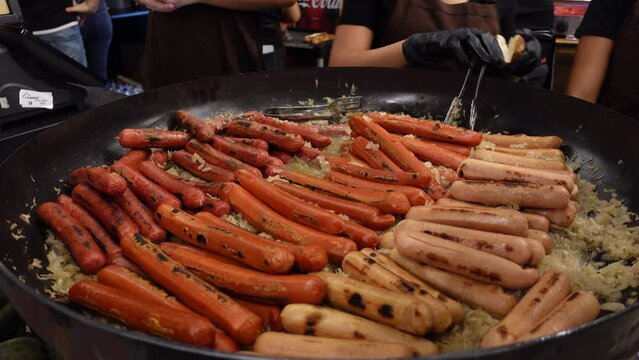 Street food hot dog - grilled German or Bavarian Nuremberg sausages with cabbage sauerkraut on a huge pan bowl at market.