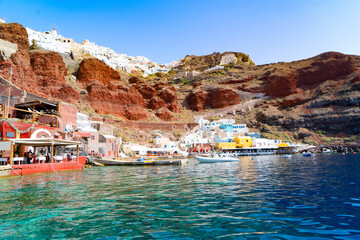 Amoudi bay with brilliant water and boats, port of Oia, Santorini Greece at sunny summer - obrazy, fototapety, plakaty