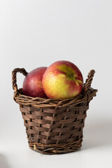 Small wicker basket with apples on a white background