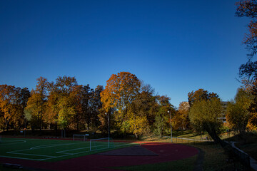 Autumn  city park with colorful trees and a football stadium in foreground, copy space in clear...