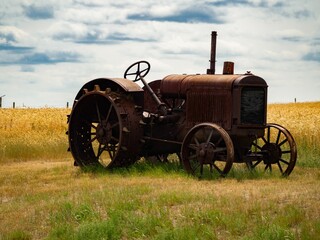 Fototapeta na wymiar Vintage tractor parked in a field of golden grain, standing alone in the open countryside