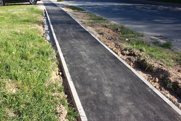 Paved asphalt pedestrian path, narrow sidewalk on the street