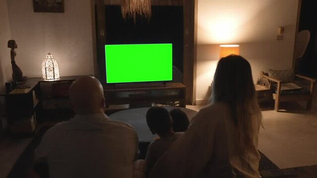 Family of Man and Woman with Children Watching TV at Home. Parents and Kids in Evening Living Room Looking at White Chroma Key of Television Screen Mockup. Rest Time of Casual Person and Small Child