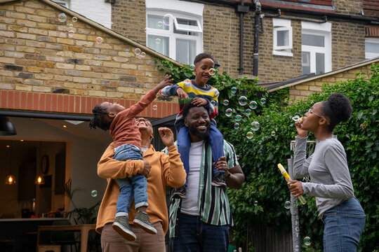 Family With Children (2-3, 6-7, 12-13) Playing With Soap Bubbles