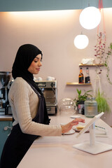 Young woman in hijab working in cafe