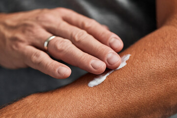 A man putting a moisturizer on his hand rubs into his skin. - obrazy, fototapety, plakaty