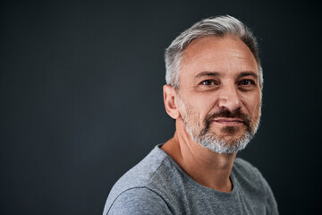 Fototapeta premium Close-up portrait of a senior man, posing on the grey background, looking at the camera.