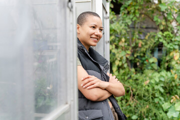 Portrait of smiling woman standing in front of greenhouse
