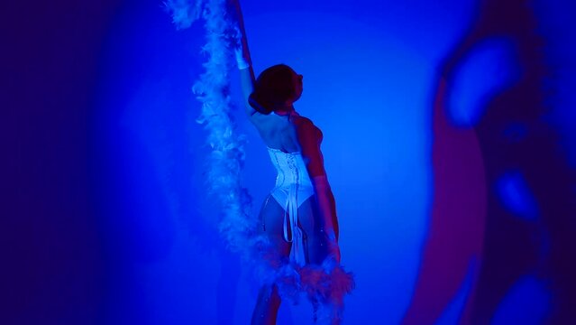 Beautiful and sexy dancer posing for the camera under blue-colored lights