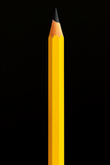 Pencil is laying on yellow surface with shadow.