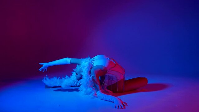 Beautiful and sexy dancer posing for the camera under blue and purple-colored lights